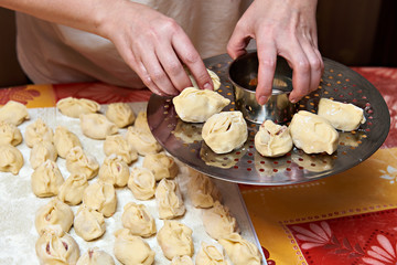 Womens hands with dumplings manti and platform for cooking