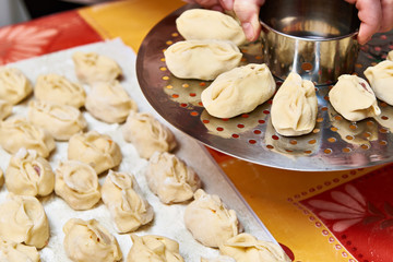 Womens hands with dumplings manti and platform for cooking