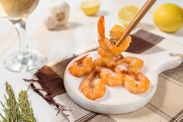 Fried shrimps with chopsticks on a white wooden board