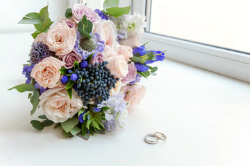 Beautiful wedding rings lie on a table against the background of a bouquet of flowers