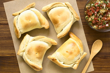 Chilenische Empanada, eine gebackene Teigtasche gefüllt mit Fleisch, Chilenische Pebre Sauce an der Seite, fotografiert mit natürlichem Licht