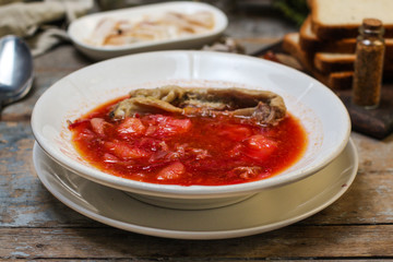 Borsch with meat in a white plate - Serving on a wood table