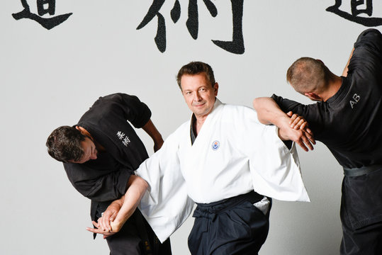 Three men in fighting position of martial art with kimono and black belts