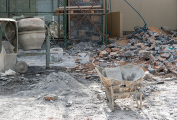 Construction site with gray wheelbarrow and portable concrete mixer.