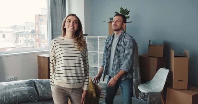 Man and woman bringing boxes into room. Young people calling dog to themselves, stroking, playing. Spaniel adoring owners.