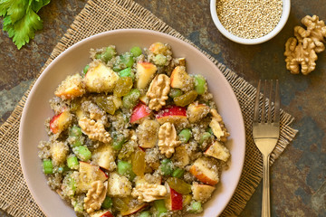 Quinoa Waldorf Salad with apple, celery, yellow raisins and walnut served on plate, photographed overhead on slate with natural light