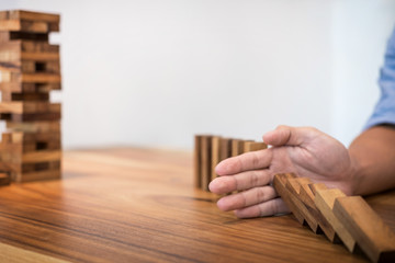 Risk and strategy in business, Close up of businessman hand stopping wooden block from falling in the line of domino