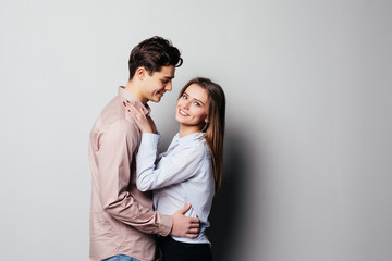 Vertical photo of two young cheerful people hugging each other against gray