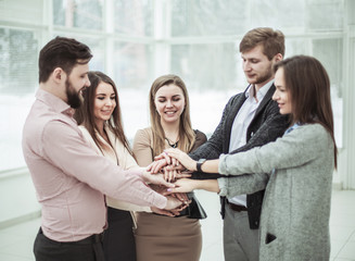 concept of teamwork:friendly business team standing in a circle, hands clasped together