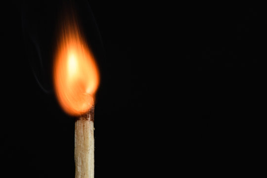 The time of a match burning with a bright flame on black background closeup