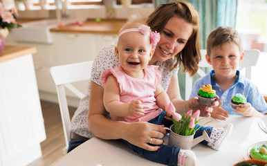 Happy children with mother eating cupcakes