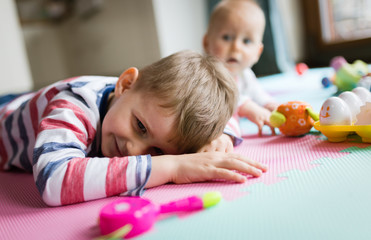 Fototapeta na wymiar Cute little children playing while sitting on carpet