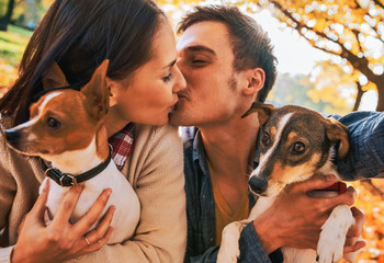 Couple with dogs making selfie while kissing in autumn park