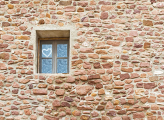 Heart in the window on the wall of the old stone house