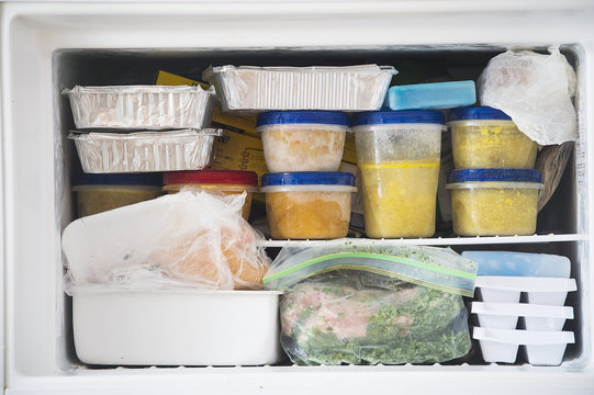 a freezer packed with chicken, soup and various frozen food