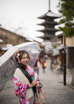 young woman in kimono holding umbrella front of yasaka pagoda