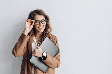 Beautiful business woman in a glasses with smile and a laptop in her hands in the office near a...
