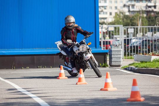 Fototapeta L-driver person driving slalom through the orange cones on motordrome on motorcycle