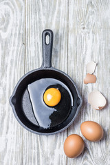 Fresh eggs in a cast iron skillet on white rustic background. Top view, space for text.
