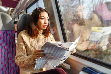 Woman tourist travels by train near window and looks at map