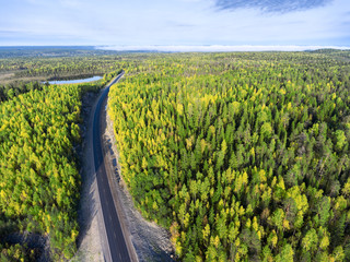 Aerial view at asphalt highway passing in rock tunnel in autumn forest of Karelia, Russia. The Kola route