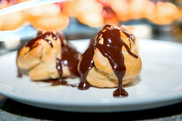 Chocolate covered vanilla cream pastry puffs close up.