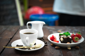 Brownie with Fresh strawberry on white plate,Hot coffee on wood background