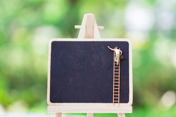 Workers climb the ladder to write text on a blackboard with copy space for text input, use as a writing background concept.