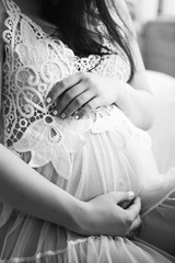 Obraz na płótnie Canvas black white photo of pregnant belly with hands in negligee