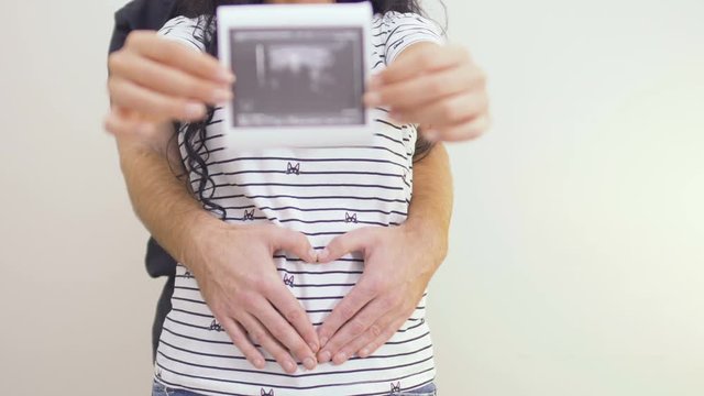 Man hugs pregnant woman with photo of ultrasound