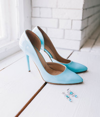 Wedding details: female wedding blue shoes and earrings on a white window sill near a brick wall - 187783442