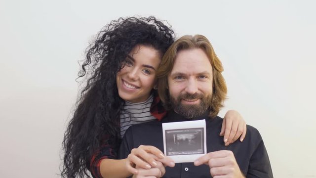 Happy young future parents with photo of ultrasound their future baby