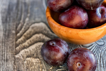 Obraz premium Garden plums in bowl on wooden table