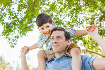 Mixed Race Father and Son Playing Piggyback Together in the Park.