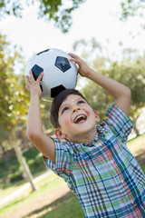 Naklejka premium Cute Young Boy Playing with Soccer Ball Outdoors in the Park.