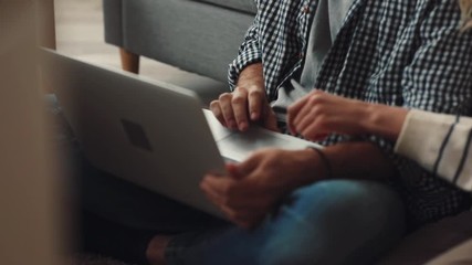 Loving girl hugging guy. Young people watching something on Internet. Pretty girl pointing to pictures with the things that she wants to see in house.