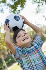 Naklejka premium Cute Young Boy Playing with Soccer Ball Outdoors in the Park.