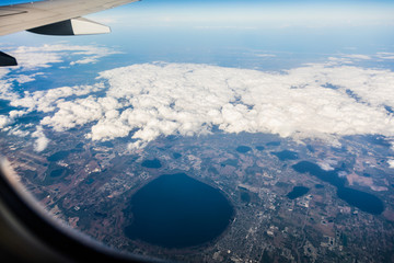 Fototapeta na wymiar Jet wing and white cloudscape in blue sky from window