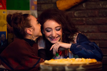 two cheerful girlfriends with pizza in  cafe