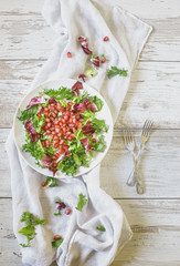 Healthy vegetarian salad with endive, mixed lettuces, arugula and pomegranate on white wooden board