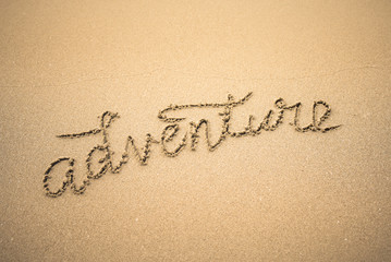 Adventure word is written on the beach sand