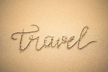 Travel word is written on the beach sand