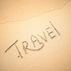 Travel word is written on the beach sand
