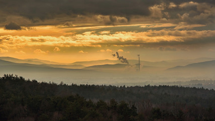 Fototapeta premium Smog hell - sunset. View from afar the city and a factory chimney with lots of smoke and smog. Europe, landscape Slovakia, Novaky. Chemical factory. Abstract. Global warming of the earth.