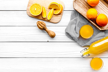 Make orange juice. Juicer, beverage in bottle and glasses near slices of oranges on white wooden background top view copy space