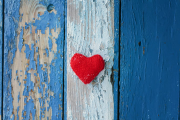 red heart made of yarn against the wall of wood with a shabby country blue paint different shades of stripes