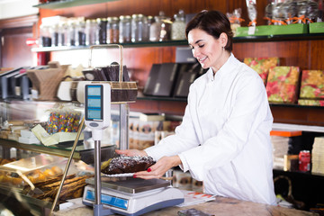 Pretty seller weighing festive chocolate cake