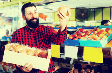 Male shop assistant demonstrating pomegranates