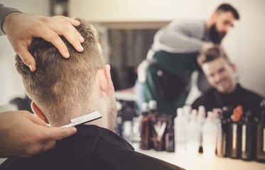 male hairdresser doing haircut for male client at hair salon