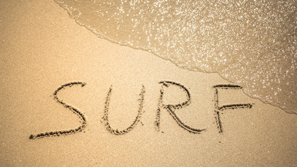 Surf word is written on the beach sand